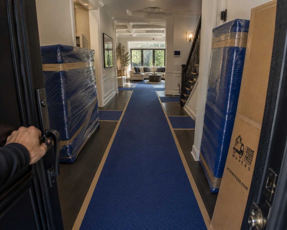 Oversized items shrink-wrapped and staged on floor runners in a home entryway